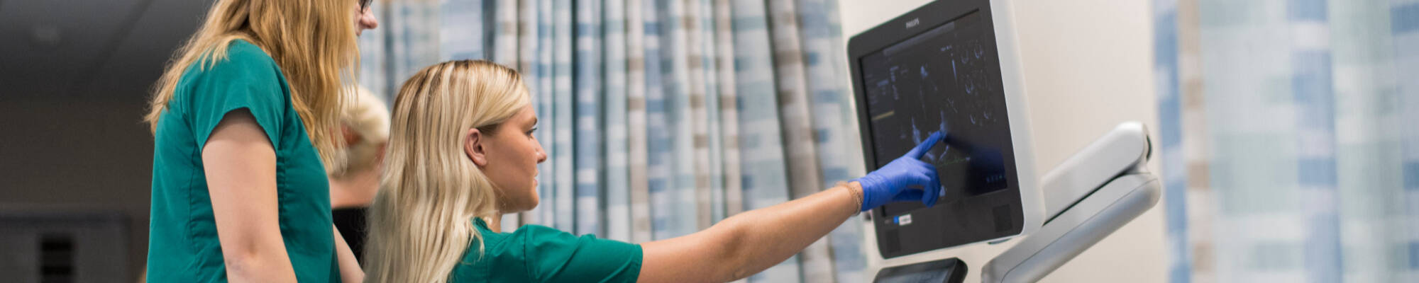 Students in a hospital setting examine a monitor